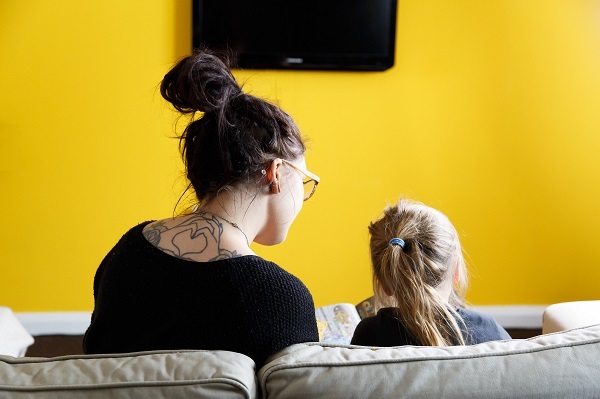 A mum reading with her daughter on a sofa