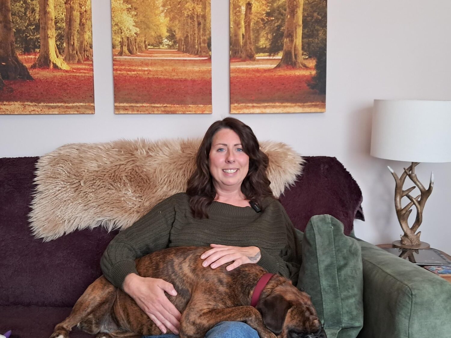 Chair of Voice of Resident Panel sitting on a sofa with a dog laying on her lap.