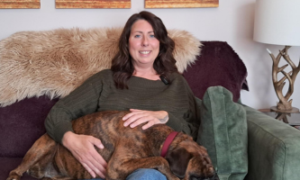 Annette, Chair of Resident Panel sitting on a sofa with a dog laying on her lap.