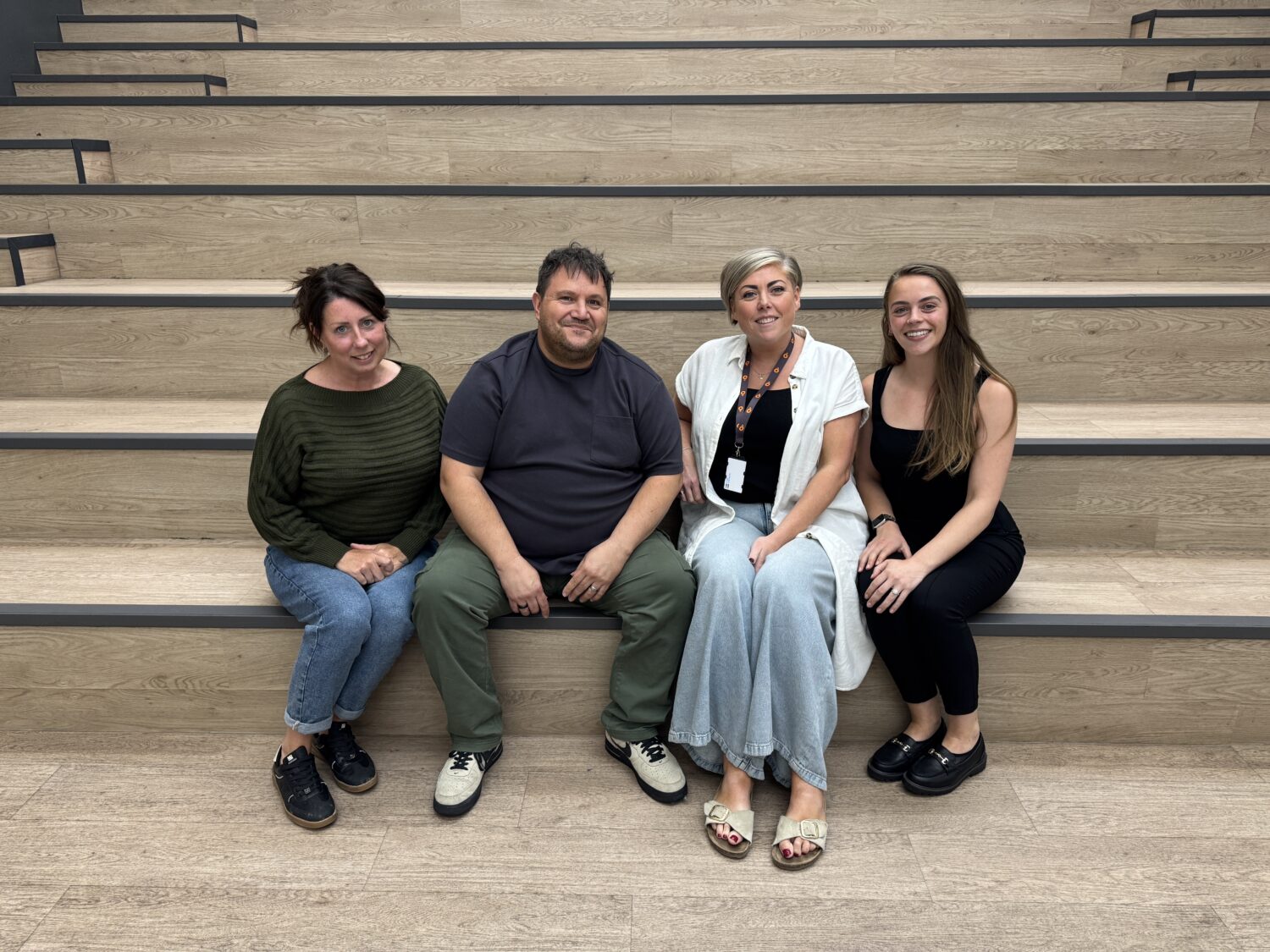 Three members of the Voice of the Resident Panel pictured with Settle's Head of People and Engagement, sitting on some steps in the Settle office.
