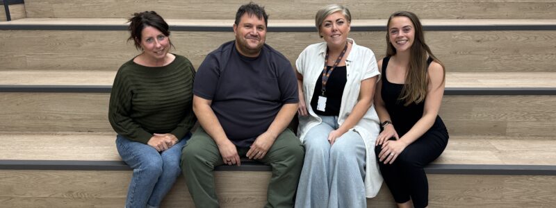 Three members of the Voice of the Resident Panel pictured with Settle's Head of People and Engagement, sitting on some steps in the Settle office.