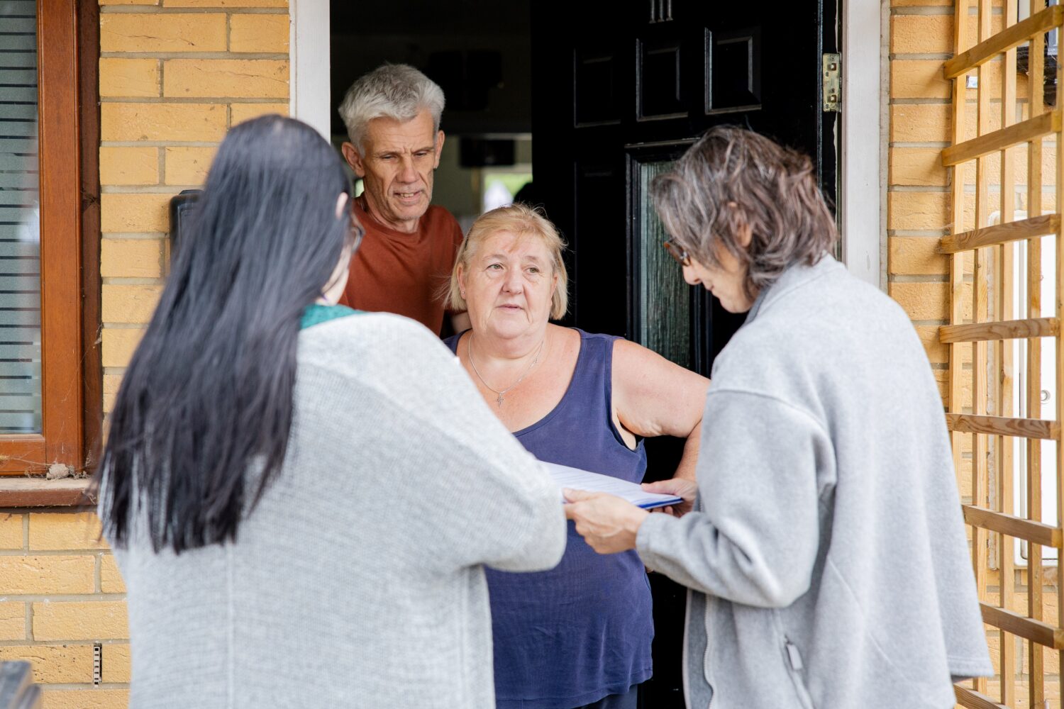 Two sSettle colleagues at an open door talking with two residents
