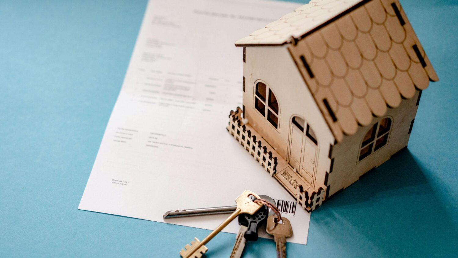 A picture of a model house, keys and piece of paper
