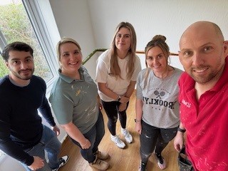 A group of Settle and Lovell colleagues standing together indoors in a brightly lit room, posing for a photo during the Icknield Way redecorating project.