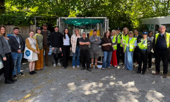 Settle colleagues with partners at Moselle House in Watford standing in a line in front of a Settle truck with bags of rubbish. 